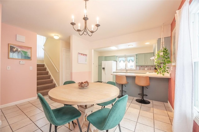 dining space featuring light tile patterned flooring, a chandelier, and sink