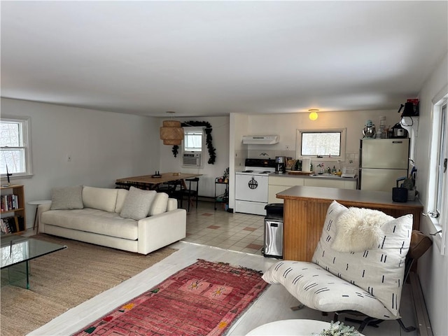 living room featuring cooling unit, light tile patterned flooring, and a wealth of natural light