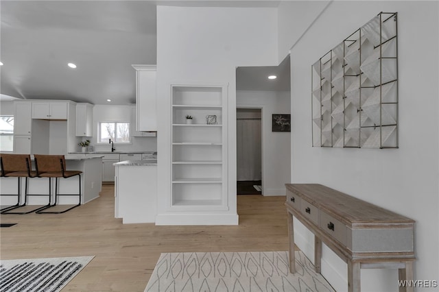 kitchen with sink, white cabinets, a kitchen bar, and light hardwood / wood-style flooring