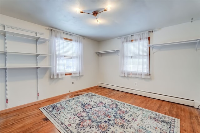 bedroom featuring light hardwood / wood-style flooring, multiple windows, and a baseboard radiator