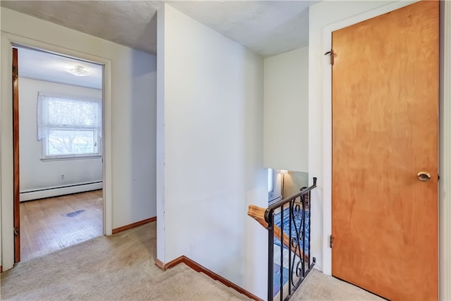 hallway featuring a baseboard radiator and light colored carpet