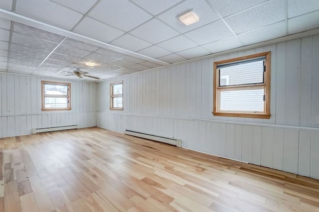 spare room with a baseboard radiator, light hardwood / wood-style floors, ceiling fan, and a paneled ceiling