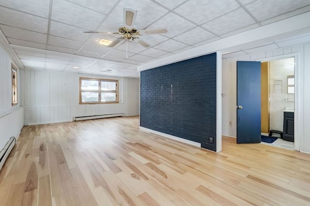 empty room with light wood-type flooring, a paneled ceiling, ceiling fan, and baseboard heating