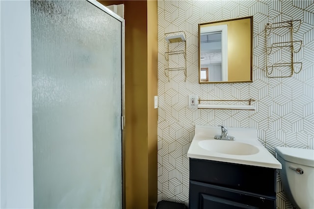 bathroom with vanity, a shower with door, tile walls, and toilet