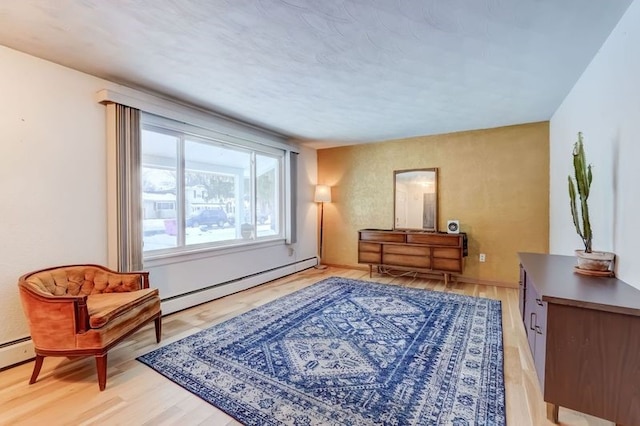 living area featuring a baseboard heating unit and light hardwood / wood-style flooring