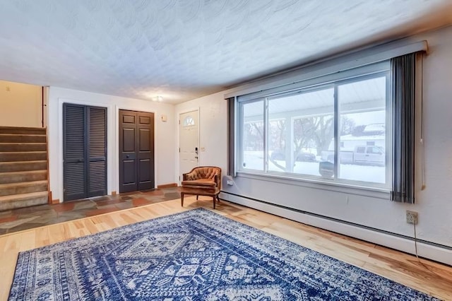 living area featuring a baseboard heating unit, hardwood / wood-style floors, and a textured ceiling