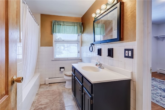 full bathroom featuring shower / tub combo with curtain, tile walls, a baseboard heating unit, vanity, and toilet