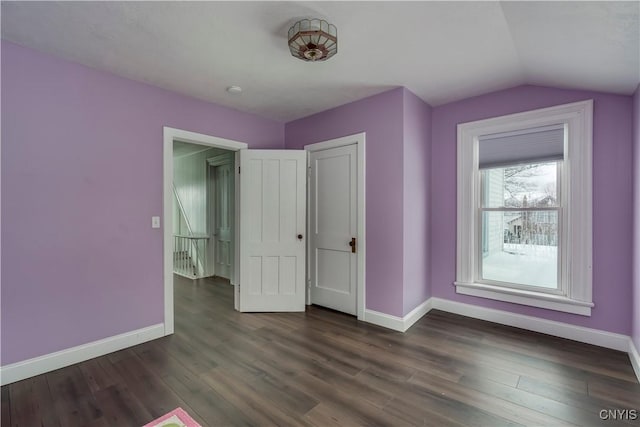 unfurnished bedroom featuring lofted ceiling, dark wood-type flooring, and a closet