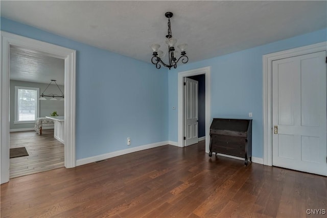 unfurnished dining area featuring dark hardwood / wood-style flooring and a chandelier