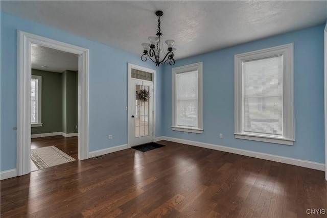 foyer entrance with dark wood-type flooring and an inviting chandelier