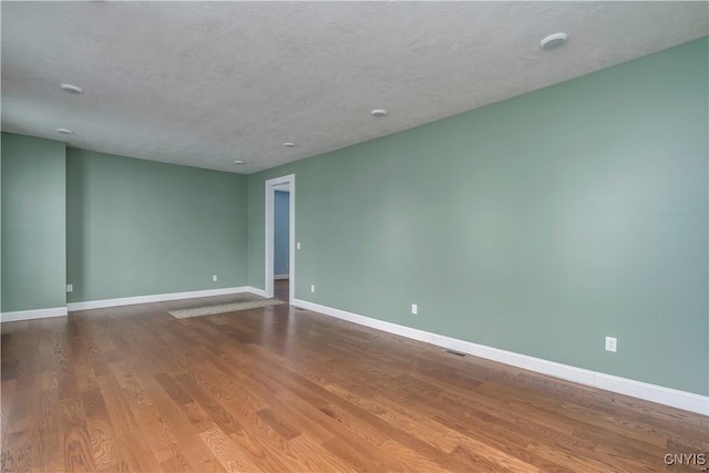 empty room with hardwood / wood-style floors and a textured ceiling