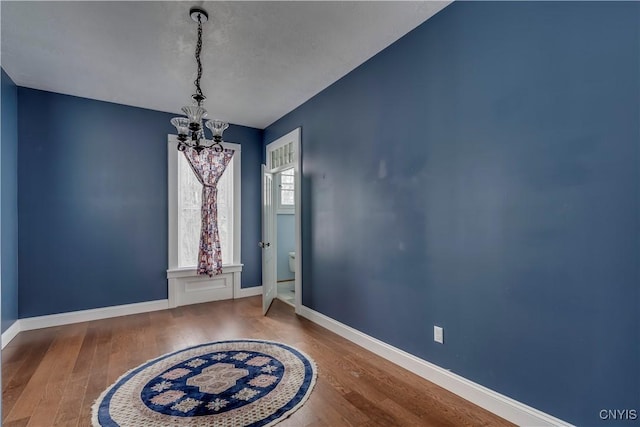 unfurnished dining area featuring hardwood / wood-style flooring and an inviting chandelier