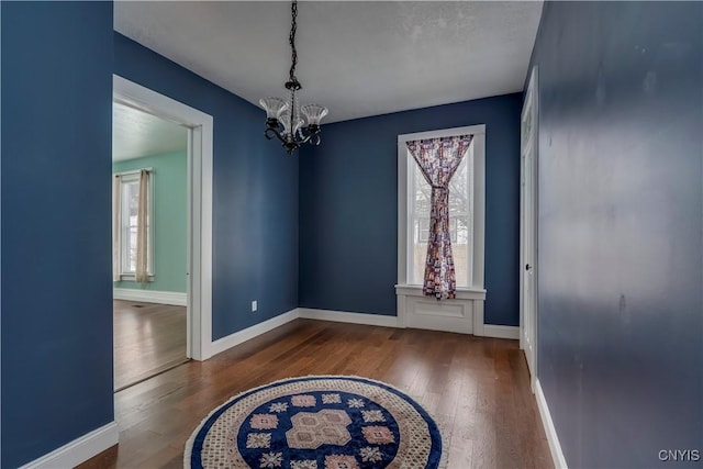 unfurnished dining area with dark hardwood / wood-style floors and a chandelier