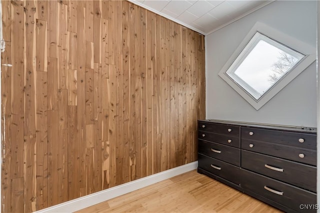 bonus room with wooden walls, a skylight, and light wood-type flooring