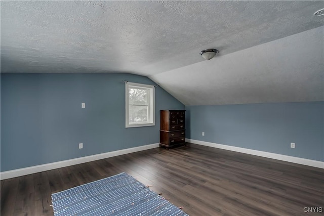 additional living space with lofted ceiling, dark hardwood / wood-style floors, and a textured ceiling