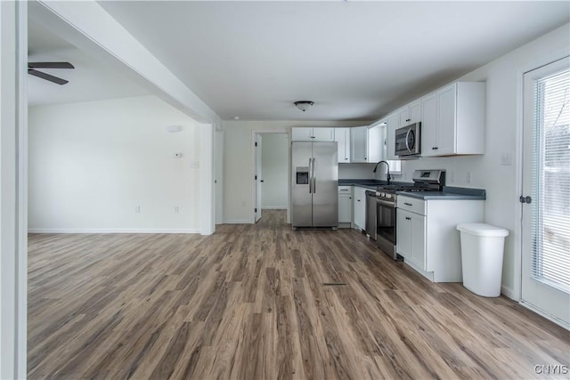 kitchen with hardwood / wood-style floors, white cabinetry, sink, ceiling fan, and stainless steel appliances