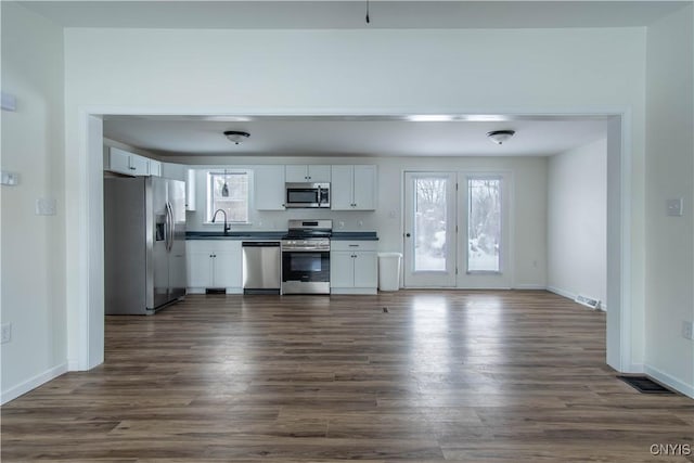 kitchen featuring stainless steel appliances, white cabinetry, sink, and dark wood-type flooring