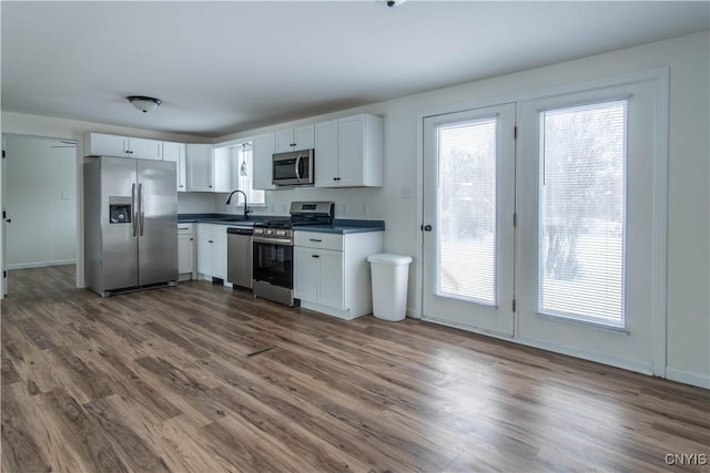 kitchen with white cabinetry, appliances with stainless steel finishes, sink, and hardwood / wood-style floors