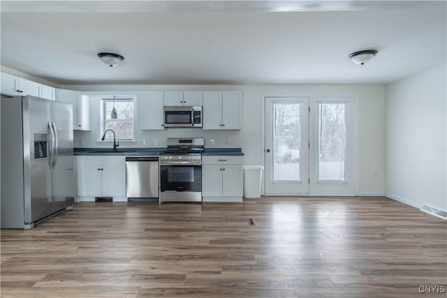 kitchen featuring stainless steel appliances, white cabinetry, and dark hardwood / wood-style floors