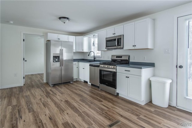 kitchen with white cabinetry, hardwood / wood-style floors, and appliances with stainless steel finishes