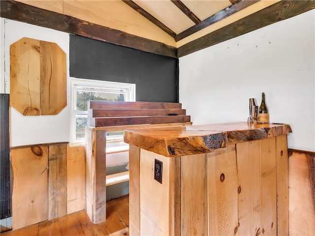 interior space with wood-type flooring, vaulted ceiling with beams, and bar area