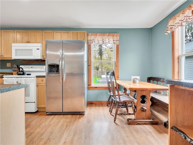 kitchen featuring white appliances, light brown cabinets, a healthy amount of sunlight, and light wood-type flooring