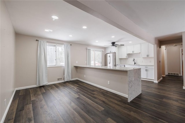 kitchen featuring sink, stainless steel refrigerator, white cabinetry, dark hardwood / wood-style floors, and kitchen peninsula