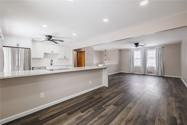 kitchen with stainless steel refrigerator, decorative light fixtures, white cabinets, dark hardwood / wood-style flooring, and light stone counters