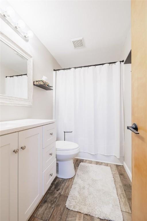 full bathroom with hardwood / wood-style flooring, vanity, shower / bath combo with shower curtain, and toilet