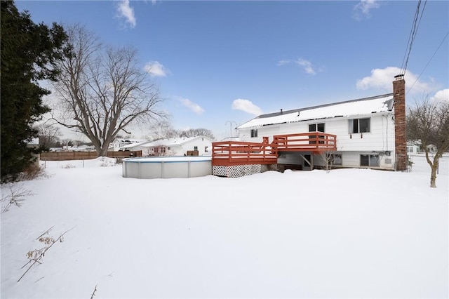 snow covered back of property with a pool side deck