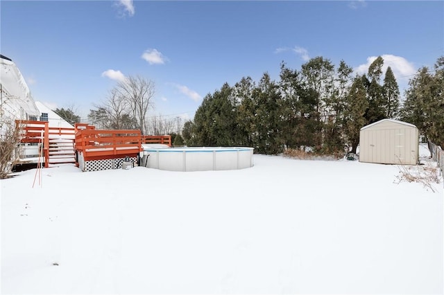 yard covered in snow with a swimming pool side deck and a storage unit