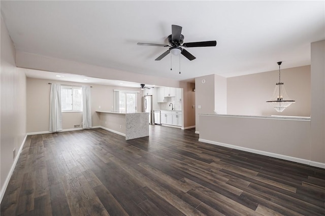 empty room with dark hardwood / wood-style floors and ceiling fan with notable chandelier