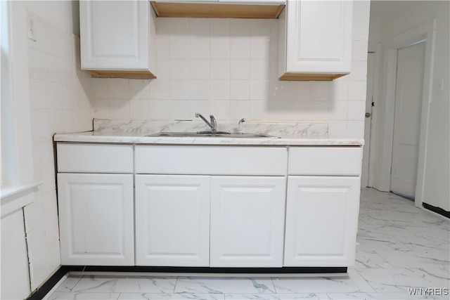 kitchen with sink, white cabinets, and backsplash