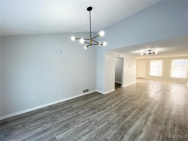 empty room with lofted ceiling, dark hardwood / wood-style floors, and a chandelier