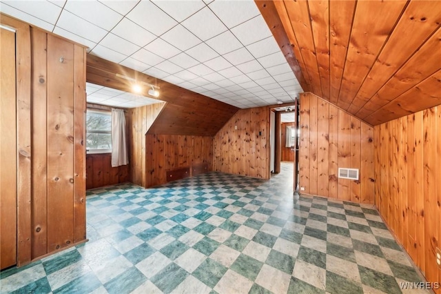 additional living space with wood ceiling, vaulted ceiling, and wood walls