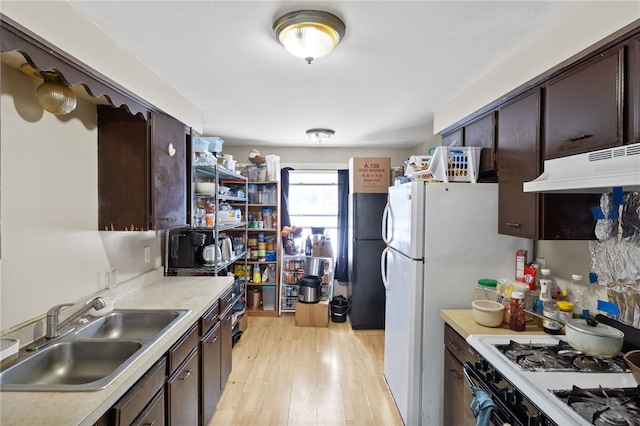 kitchen featuring range with gas stovetop, sink, black fridge, dark brown cabinets, and light wood-type flooring