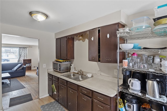 kitchen featuring sink, dark brown cabinetry, and light wood-type flooring