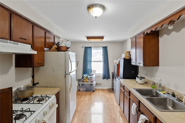 kitchen featuring white gas range oven, sink, and light wood-type flooring