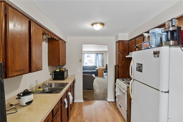 kitchen with sink, white appliances, and light hardwood / wood-style flooring