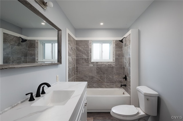 full bathroom featuring vanity, tiled shower / bath, and toilet