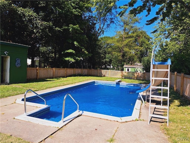 view of swimming pool with a water slide, a shed, and a lawn