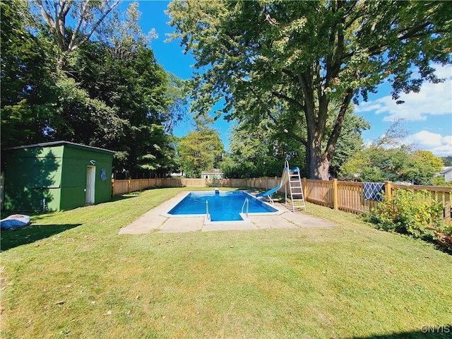 view of swimming pool with a patio, a water slide, a lawn, and a shed