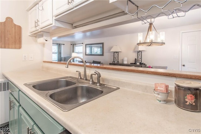 kitchen with pendant lighting, sink, dishwashing machine, white cabinetry, and green cabinetry