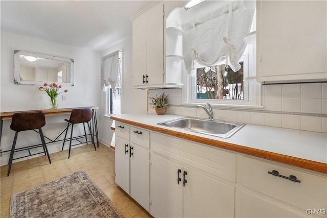 kitchen featuring backsplash, sink, and white cabinets