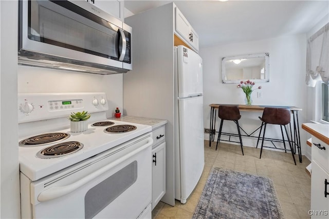 kitchen featuring white cabinetry, white appliances, and a breakfast bar