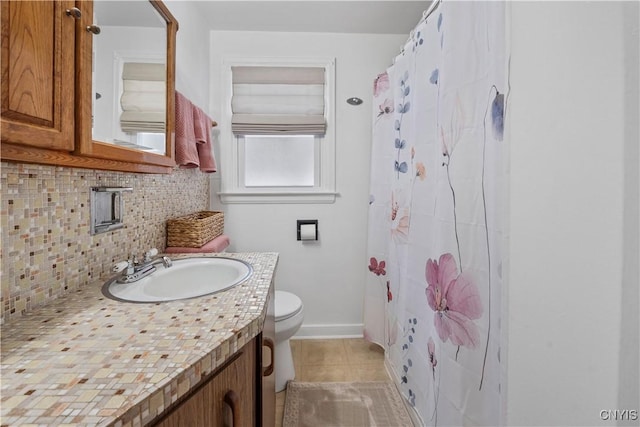 bathroom featuring tile patterned flooring, vanity, decorative backsplash, toilet, and walk in shower