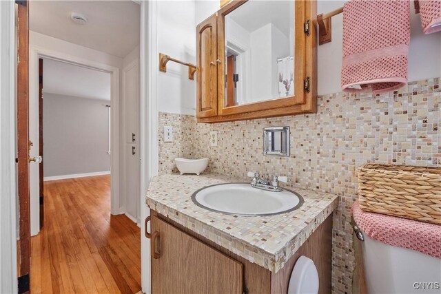 bathroom with wood-type flooring, decorative backsplash, and vanity