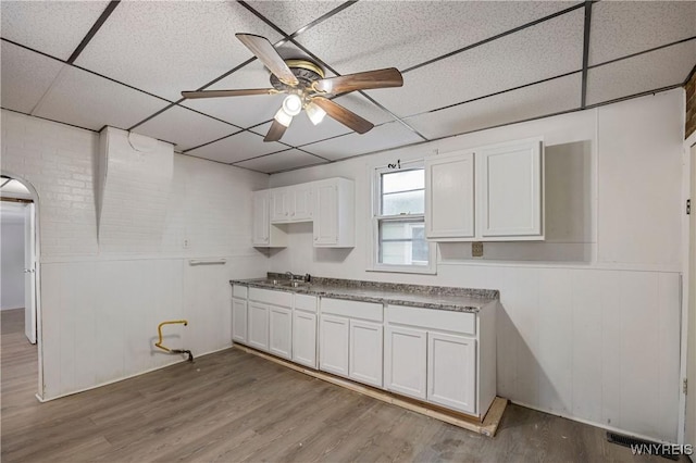 kitchen featuring ceiling fan, a drop ceiling, light hardwood / wood-style flooring, and white cabinets