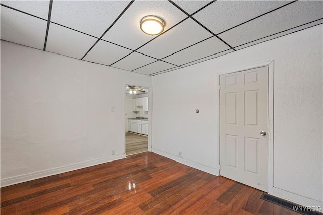 empty room featuring ceiling fan, a paneled ceiling, and dark hardwood / wood-style floors