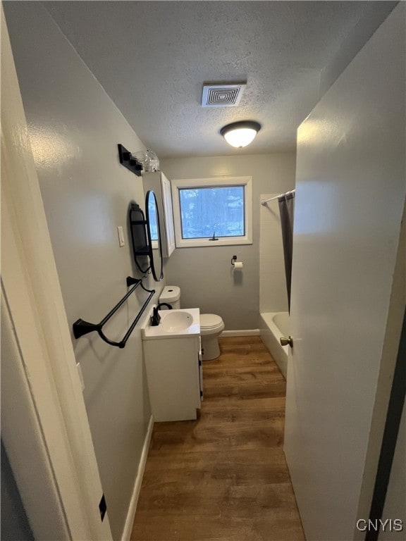 bathroom with vanity, toilet, wood-type flooring, and a textured ceiling